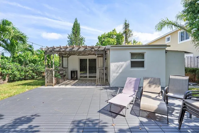 a patio with a table and chairs and potted plants