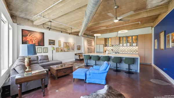 a living room with furniture kitchen view and a large window