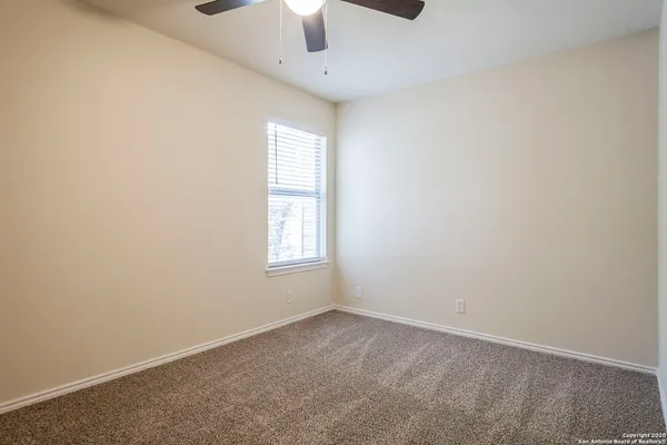 an empty room with a window and a ceiling fan