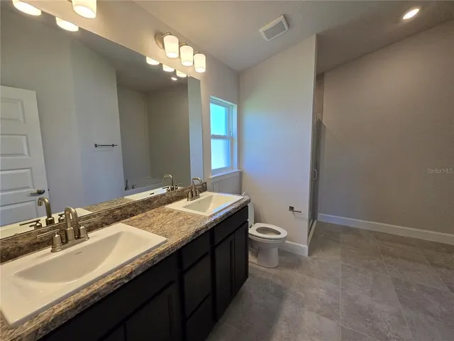 a bathroom with a granite countertop sink a toilet and shower