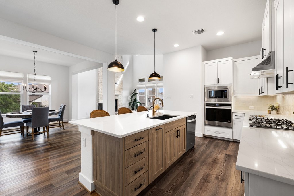305 Avena Trail Austin, TX 78738 - Photo 21 of 40 a large kitchen with stainless steel appliances kitchen island granite countertop a large island a stove a refrigerator a sink and a dining table with wooden floor