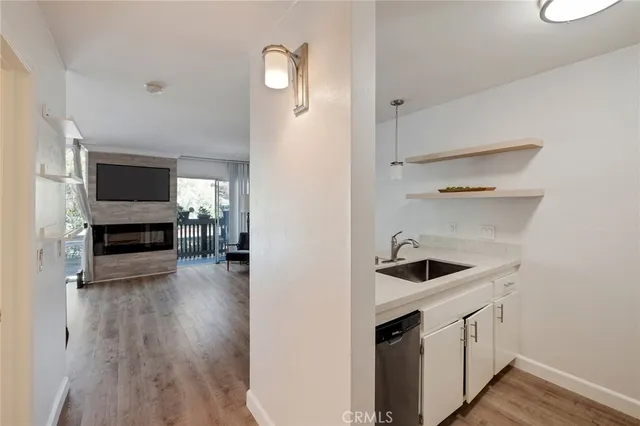 a kitchen with stainless steel appliances granite countertop a stove a sink dishwasher and white cabinets with wooden floor