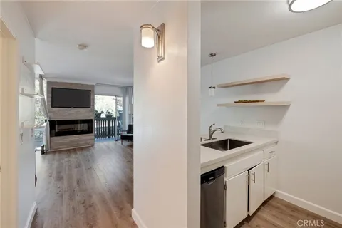 a kitchen with stainless steel appliances granite countertop a stove a sink dishwasher and white cabinets with wooden floor