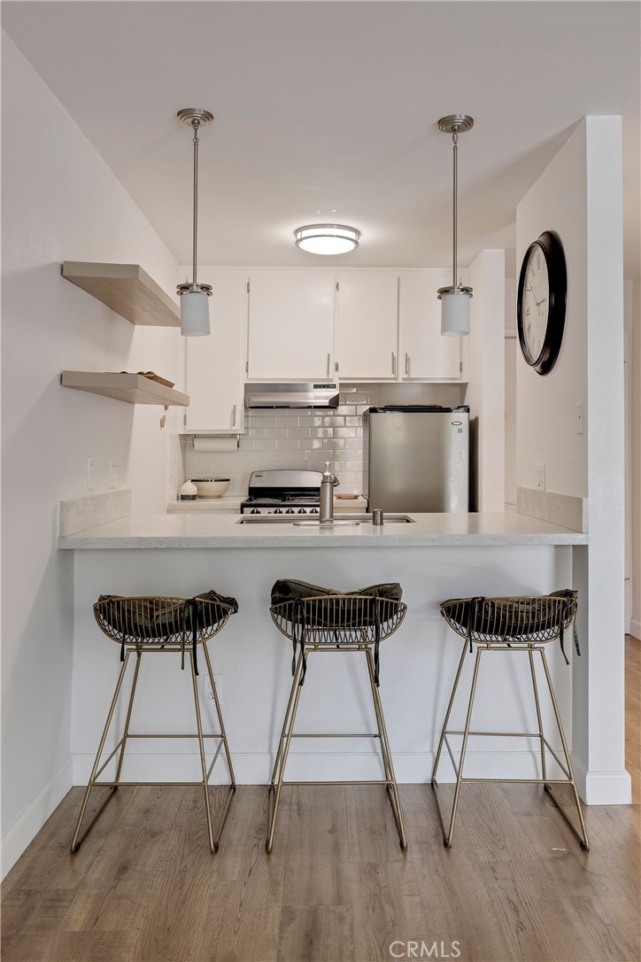 3604 West Estates Lane, Unit 114 Rolling Hills Estates, CA 90274 - Photo 20 of 59 a kitchen with stainless steel appliances granite countertop a stove a sink dishwasher and white cabinets with wooden floor