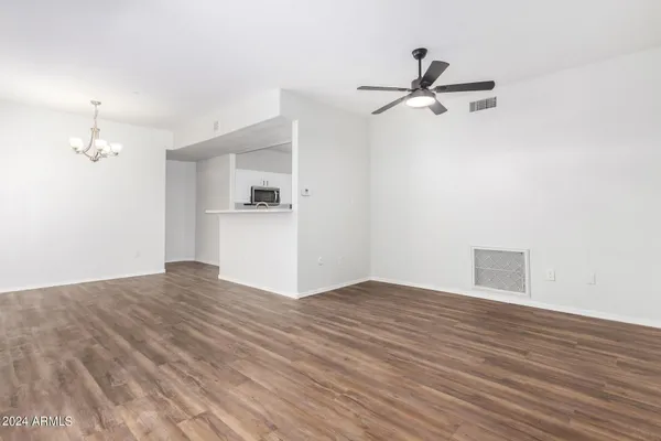 a view of empty room with wooden floor and kitchen