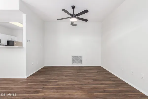 a view of a room with wooden floor ceiling fan and window