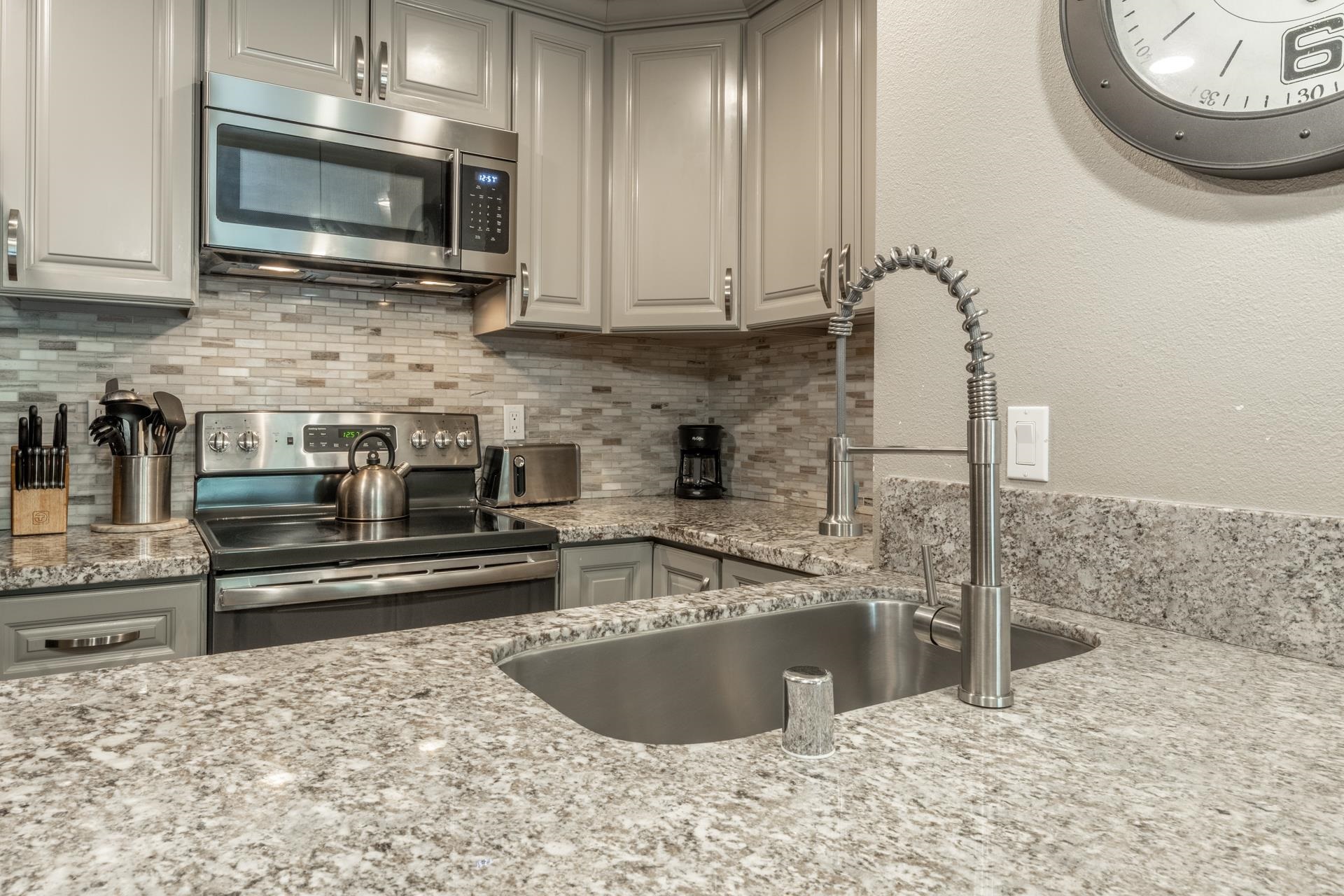 2499 Sierra Nevada Road, Unit S1 Mammoth Lakes, CA 93546 - Photo 11 of 38 Kitchen with stainless steel appliances, light stone countertops, backsplash, gray cabinets, and a textured wall