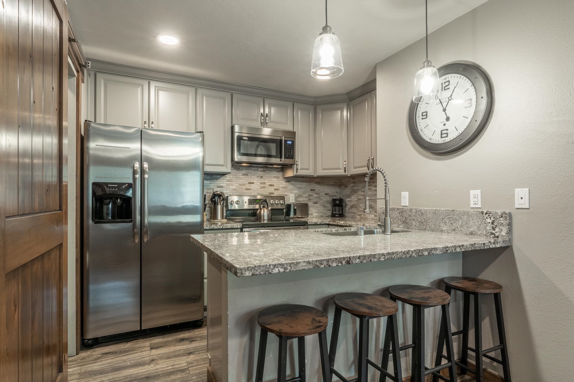 2499 Sierra Nevada Road, Unit S1 Mammoth Lakes, CA 93546 - Photo 14 of 38 Kitchen featuring a breakfast bar, stainless steel appliances, light stone counters, a peninsula, and tasteful backsplash