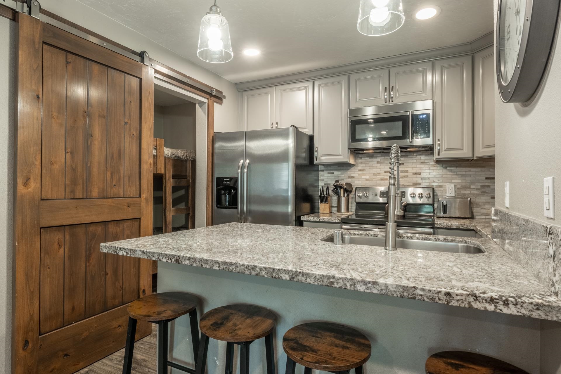 2499 Sierra Nevada Road, Unit S1 Mammoth Lakes, CA 93546 - Photo 15 of 38 Kitchen featuring a kitchen breakfast bar, stainless steel appliances, a peninsula, and light stone counters
