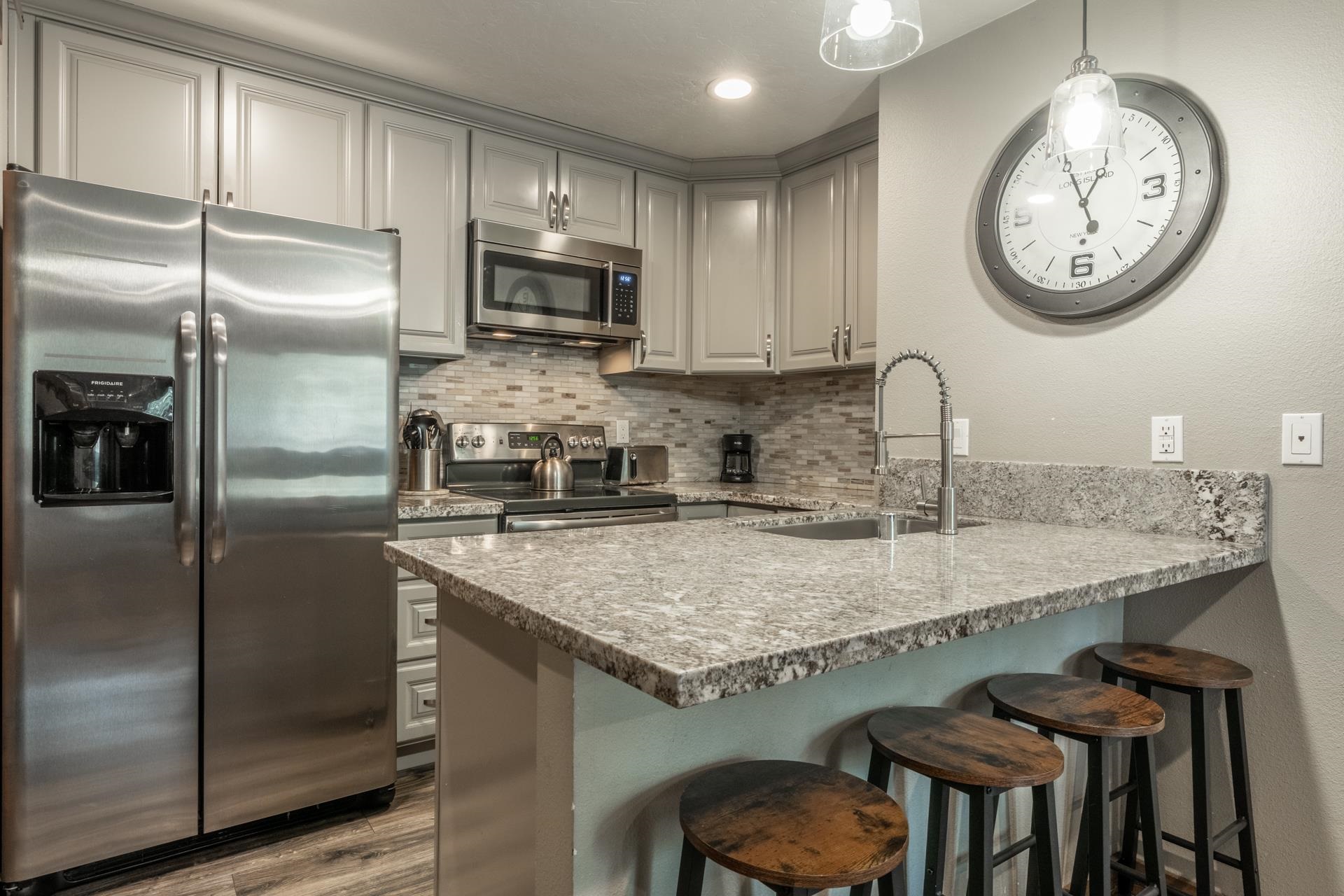 2499 Sierra Nevada Road, Unit S1 Mammoth Lakes, CA 93546 - Photo 10 of 38 Kitchen featuring stainless steel appliances, a kitchen breakfast bar, a peninsula, light stone counters, and tasteful backsplash
