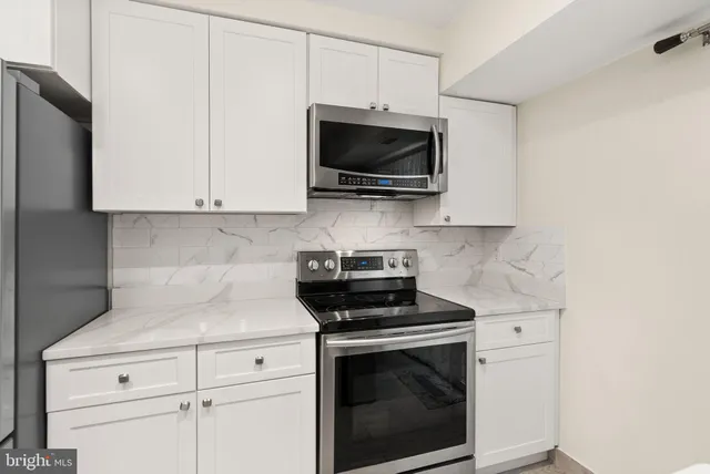 a kitchen with stainless steel appliances white cabinets and a stove top oven