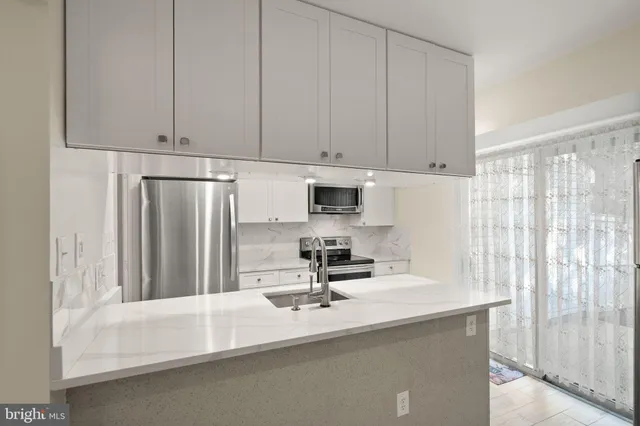 a kitchen with stainless steel appliances a sink a refrigerator and a granite counter tops
