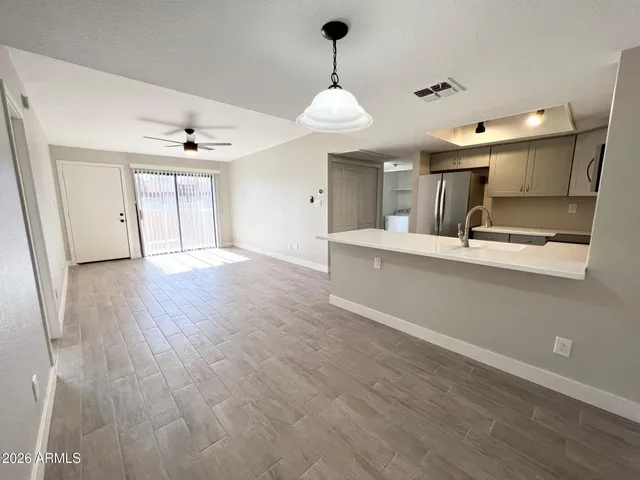 a large kitchen with stainless steel appliances a large counter top a sink and a chandelier