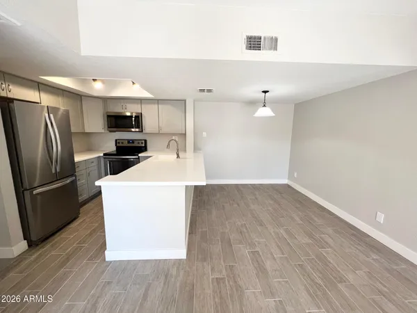 a kitchen with kitchen island a sink wooden floor and stainless steel appliances