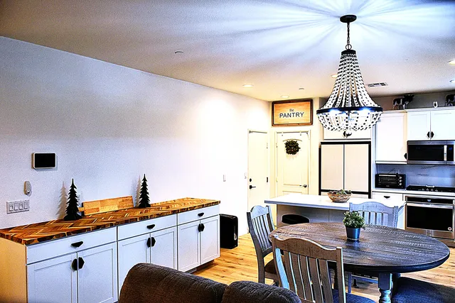 a kitchen with stainless steel appliances granite countertop a sink dishwasher a dining table and chairs with wooden floor