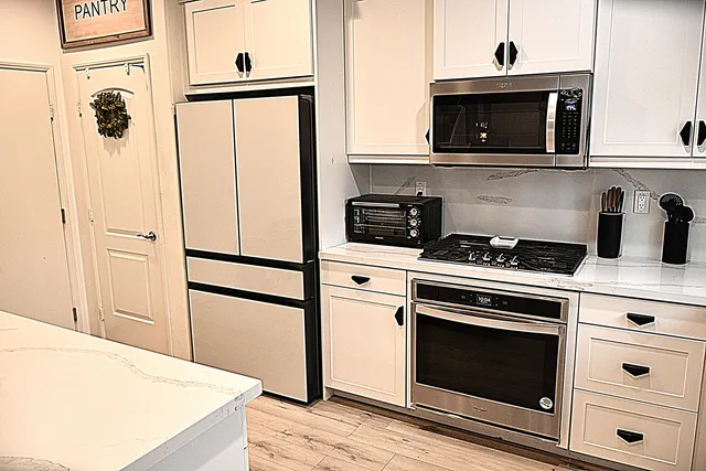 a kitchen with stainless steel appliances white cabinets and white appliances
