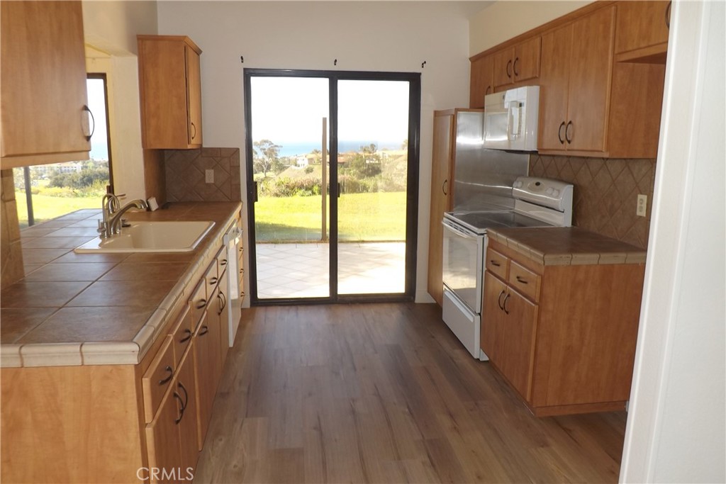 130 Avenida Adobe San Clemente, CA 92672 - Photo 13 of 26 a kitchen with stainless steel appliances granite countertop a stove a sink and a refrigerator with wooden floor