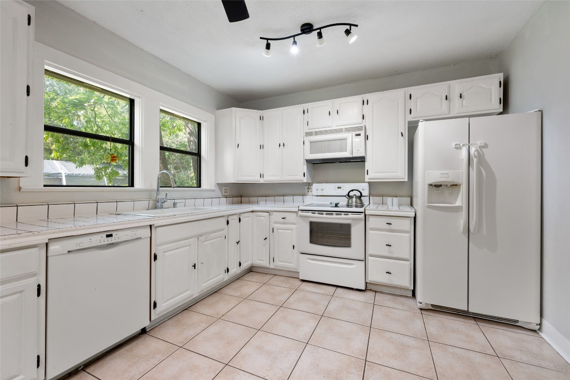 555 Hopewell Road Bertram, TX 78605 - Photo 12 of 21 Kitchen featuring white appliances, white cabinetry, light tile patterned floors, and tile countertops