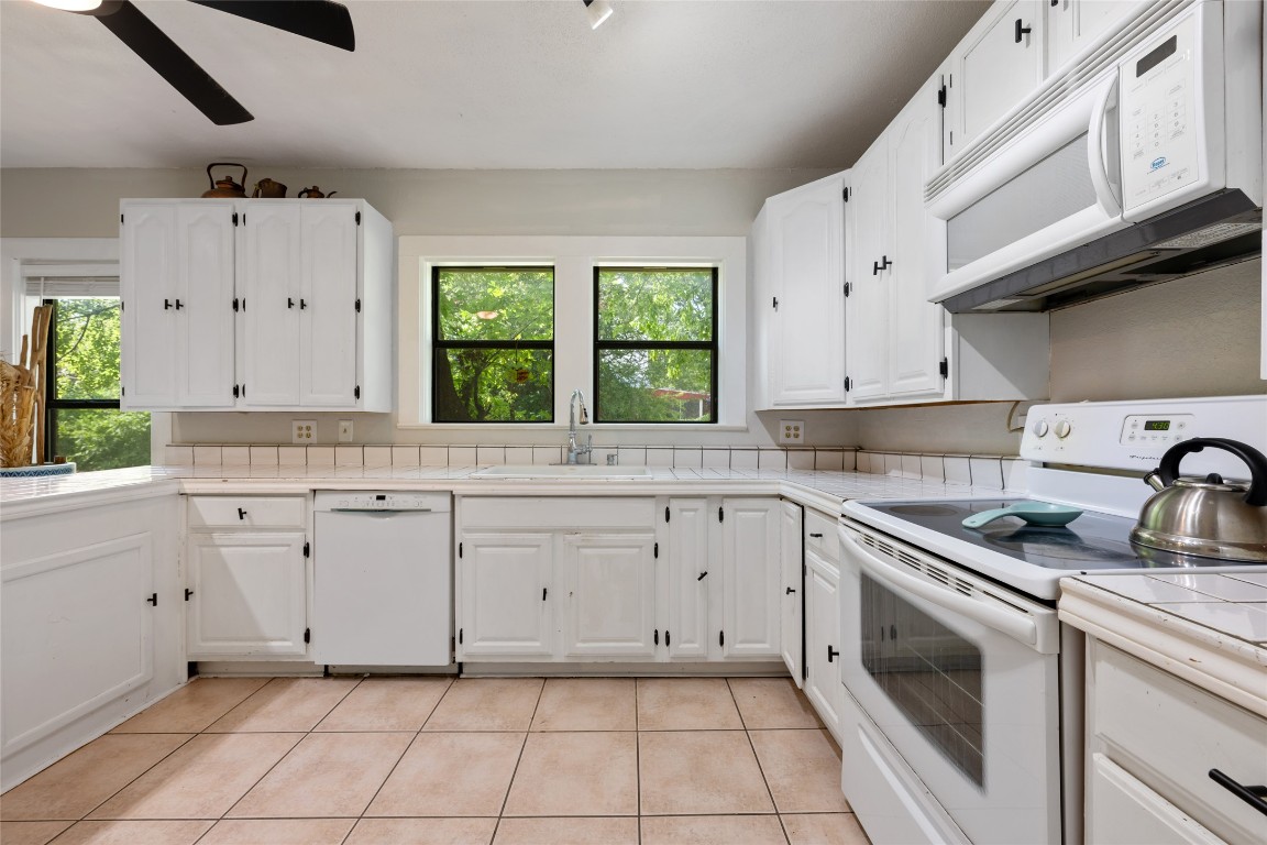 555 Hopewell Road Bertram, TX 78605 - Photo 13 of 21 Kitchen with tile counters, white appliances, white cabinets, and light tile patterned floors