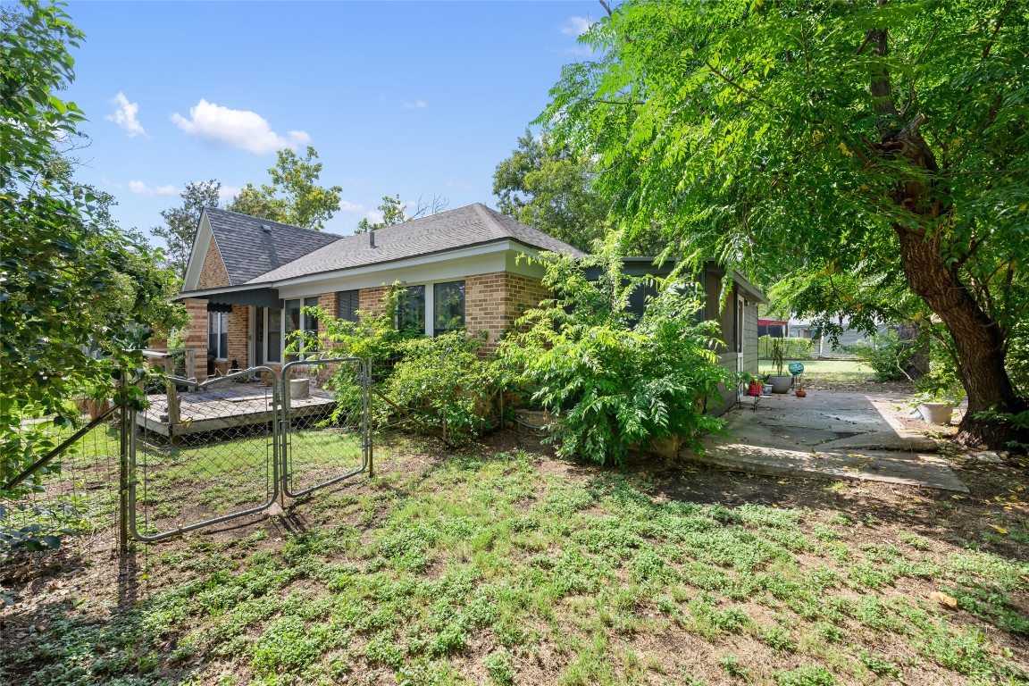 555 Hopewell Road Bertram, TX 78605 - Photo 20 of 21 Back of property with brick siding, roof with shingles, a gate, and a wooden deck