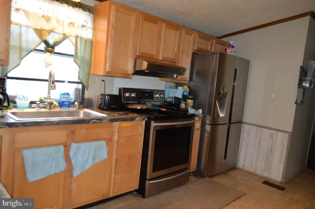 a kitchen with stainless steel appliances a refrigerator a sink a stove and cabinets