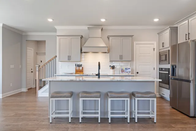 a kitchen with stainless steel appliances granite countertop a table chairs sink and cabinets