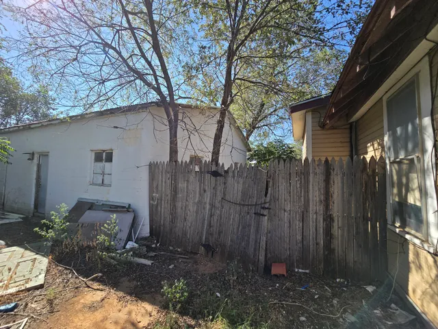 a view of a house with a backyard and wooden fence