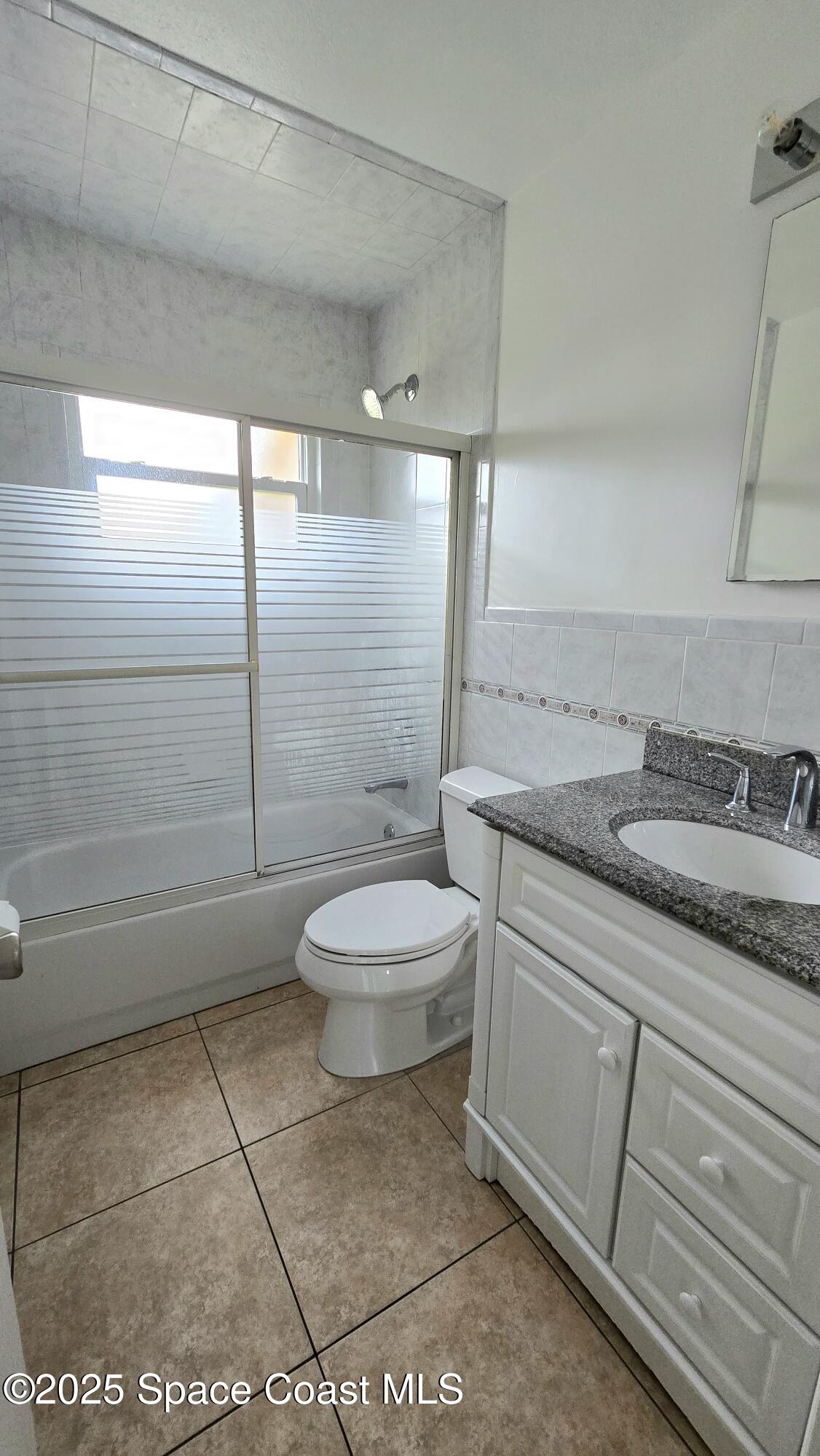 535 Lee Avenue, Unit A Satellite Beach, FL 32937 - Photo 8 of 12 a bathroom with a granite countertop sink a toilet and shower