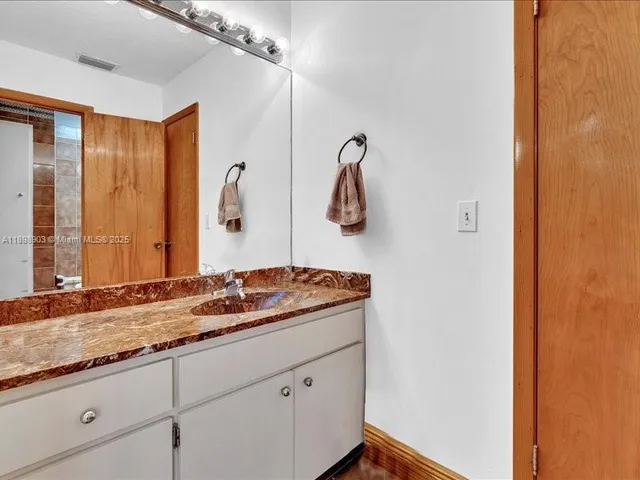 a bathroom with a granite countertop sink and a mirror