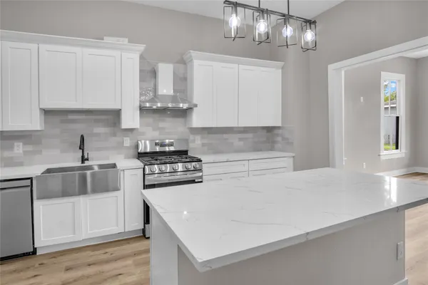 a kitchen with stainless steel appliances a stove a sink and white cabinets
