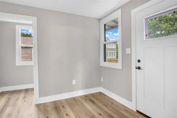 a view of an empty room with wooden floor and a window