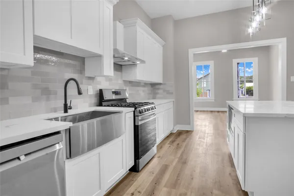 a kitchen with stainless steel appliances granite countertop a sink a stove top oven and wooden floors