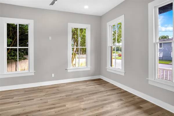 an empty room with wooden floor and windows