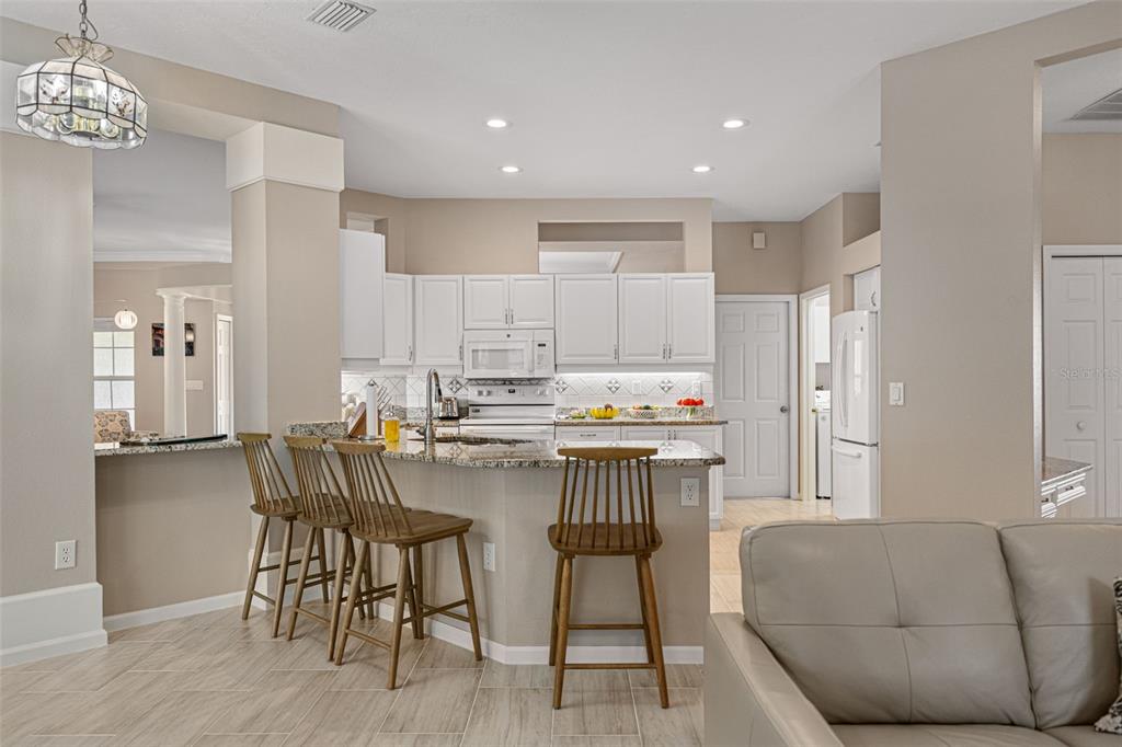 603 Pine Ranch East Road Osprey, FL 34229 - Photo 18 of 37 a kitchen with a table chairs refrigerator and microwave