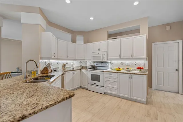 a kitchen with granite countertop a sink and white cabinets