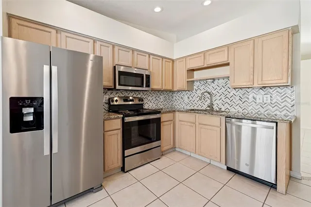 a kitchen with stainless steel appliances granite countertop a refrigerator sink and stove