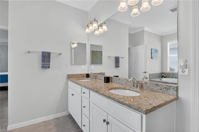 a bathroom with a granite countertop double vanity and a mirror