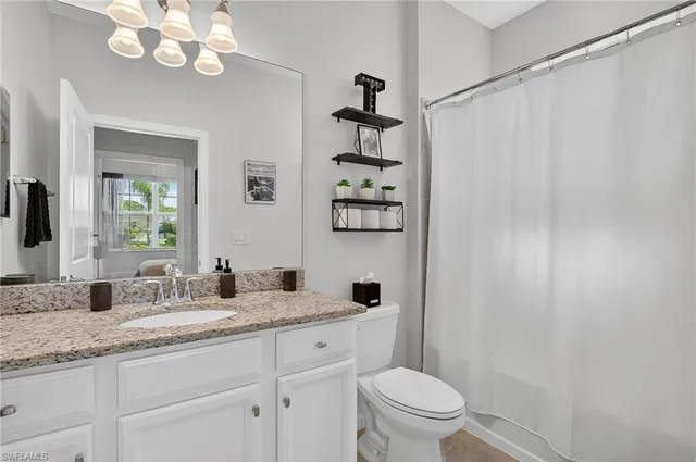 a bathroom with a granite countertop sink a toilet and a mirror