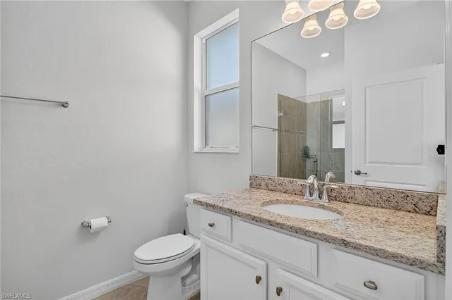 a bathroom with a granite countertop sink a toilet and a mirror