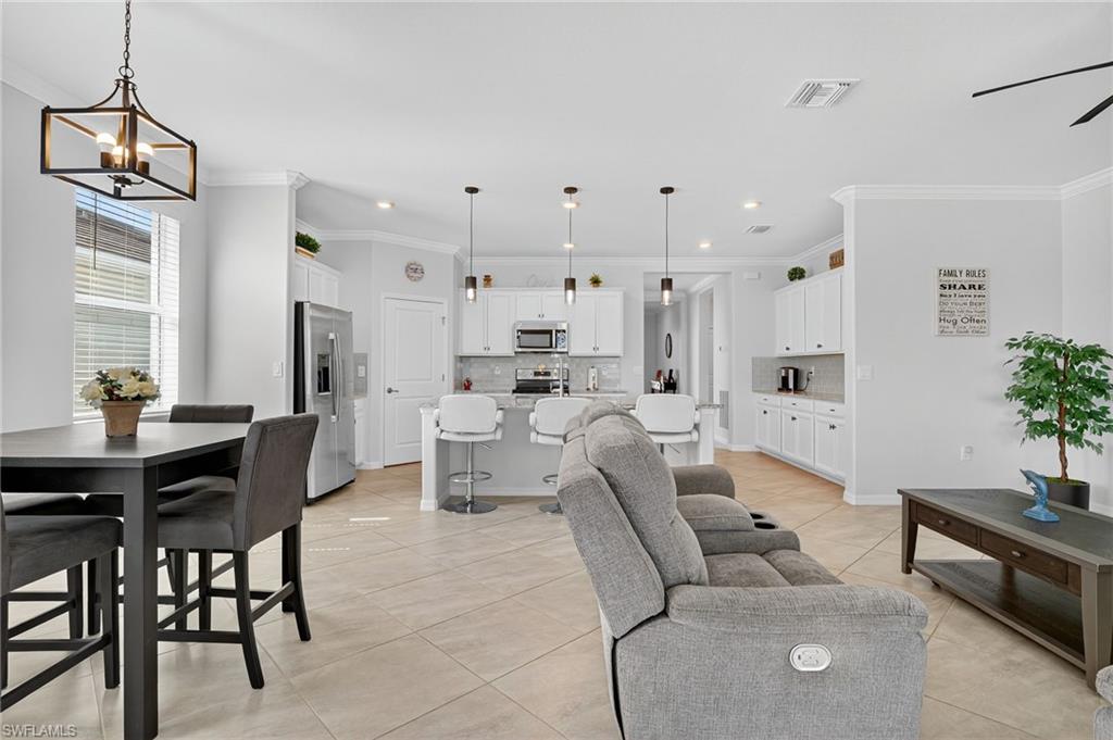 2130 Hamlin Street Naples, FL 34120 - Photo 4 of 40 a living room with furniture a dining table a rug a potted plant and a window
