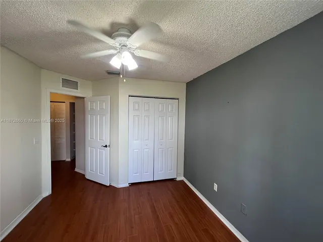 an empty room with wooden floor fan and windows