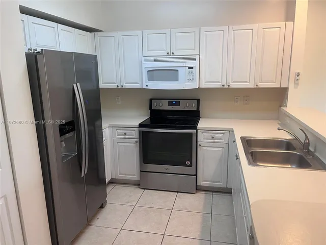 a kitchen with a refrigerator sink and cabinets