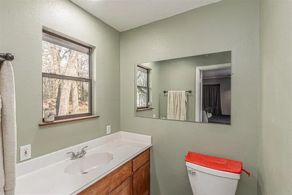a bathroom with a toilet a sink a mirror and a window