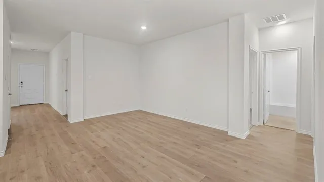 a view of an empty room with wooden floor and closet