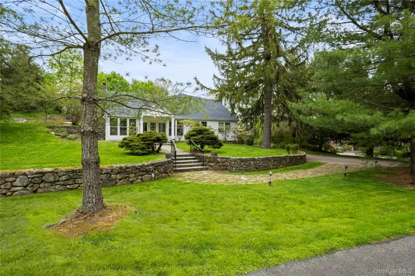 a view of a house with a big yard potted plants and large tree