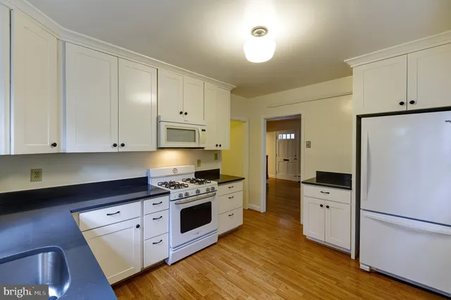 a kitchen with white cabinets and white appliances