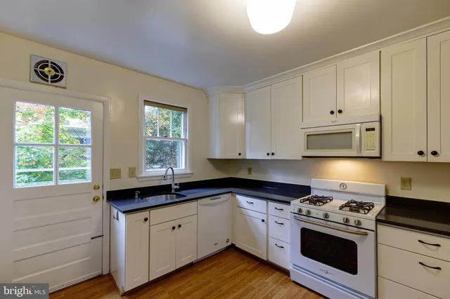 a kitchen with granite countertop white cabinets and white appliances