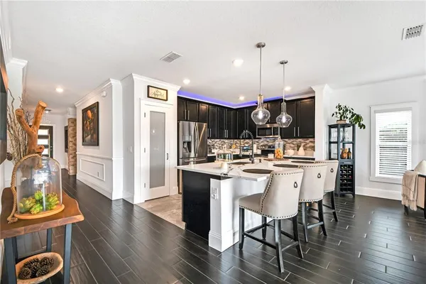 a kitchen with stainless steel appliances a dining table chairs stove and refrigerator