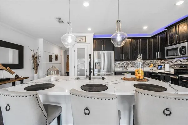 a kitchen with kitchen island a sink a stove and chairs with wooden floor