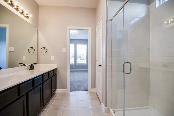 a spacious bathroom with a double vanity sink a mirror and shower